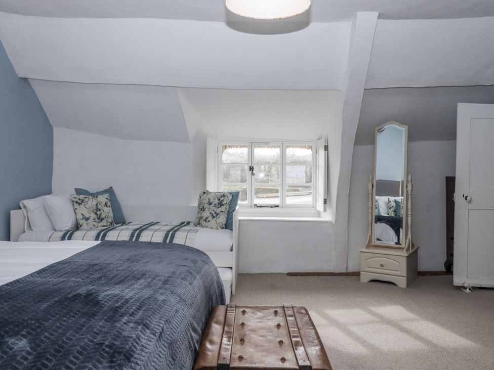 A bedroom with a bed, mirror and window at Westacombe Farm in Dunsford