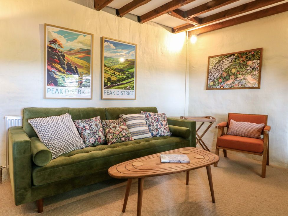 A living room with a green couch and wooden coffee table at Chimney Cottage in Winster