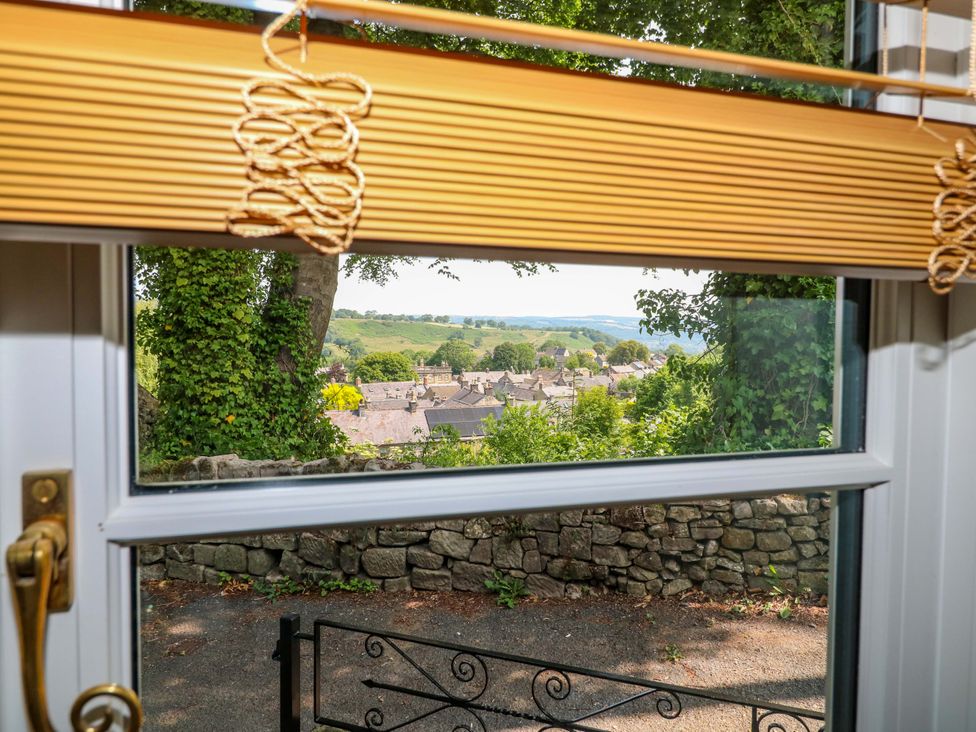 A view from a window showing houses and hills at Chimney Cottage Winster