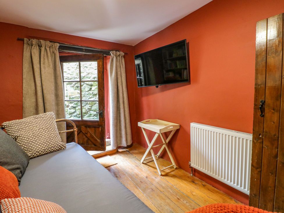 A living room with a sofa and television at Chimney Cottage in Winster