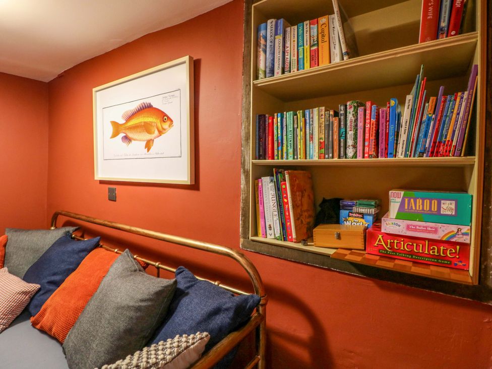 A snug area with a sofa and bookshelves at Chimney Cottage in Winster
