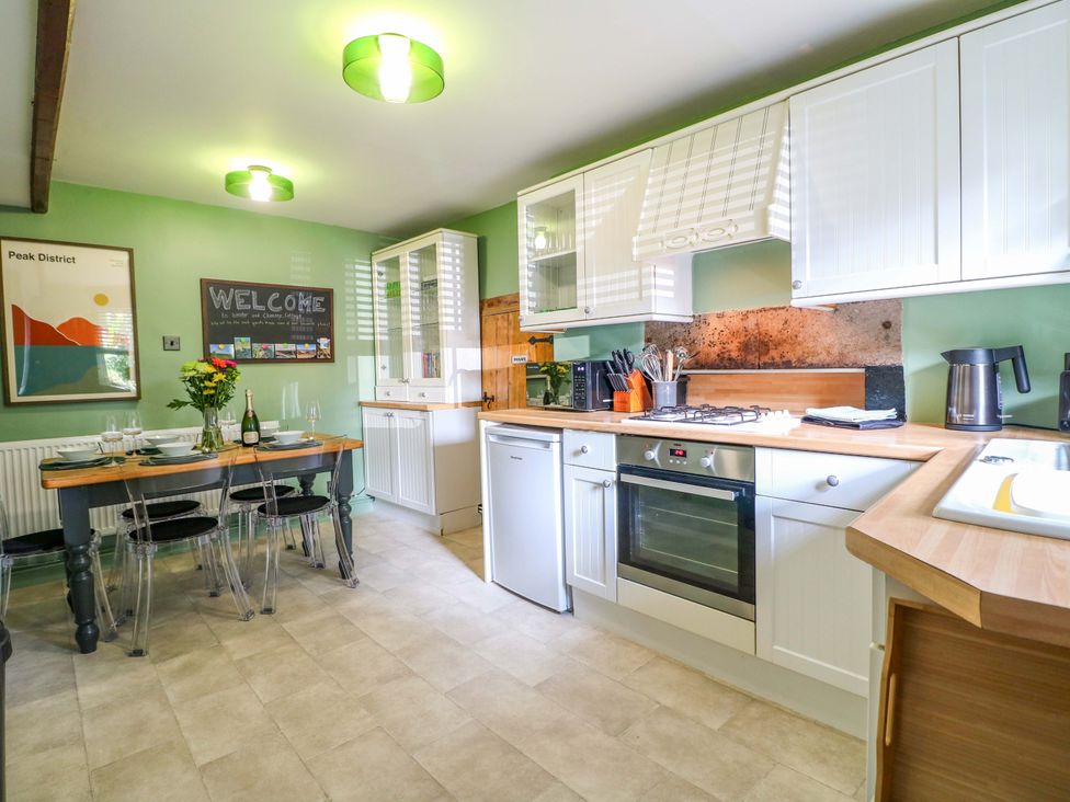 A kitchen with dining table and appliances at Chimney Cottage in Winster