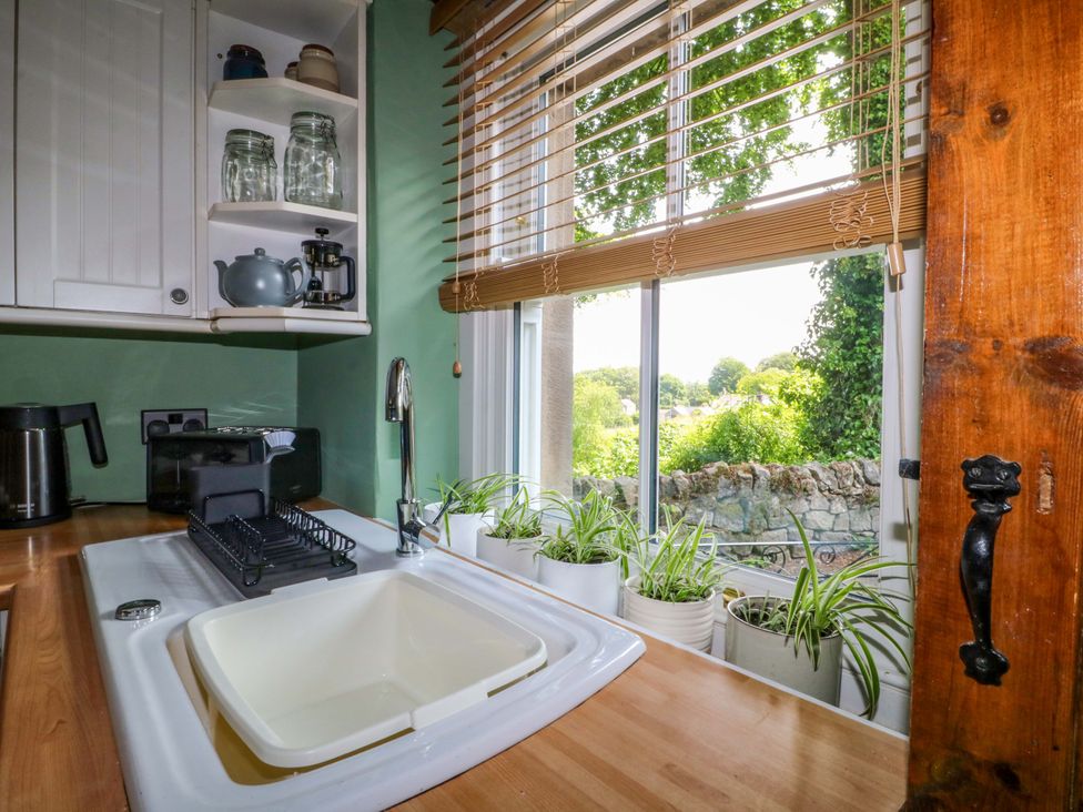 A kitchen with a sink and shelves at Chimney Cottage in Winster