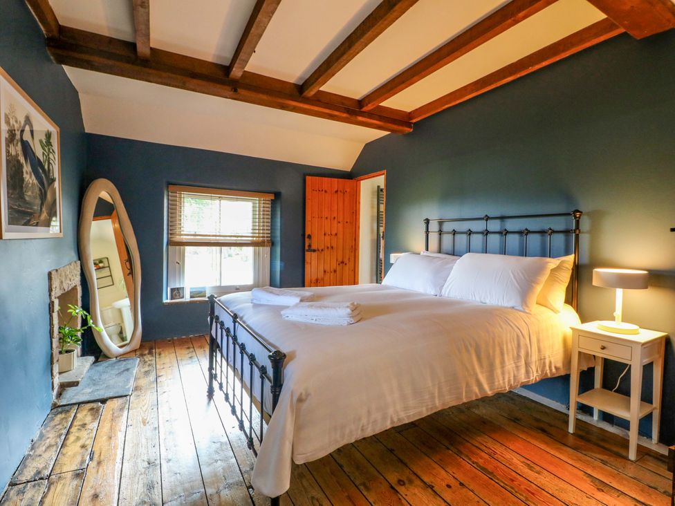 A bedroom with a bed and a mirror at Chimney Cottage in Winster