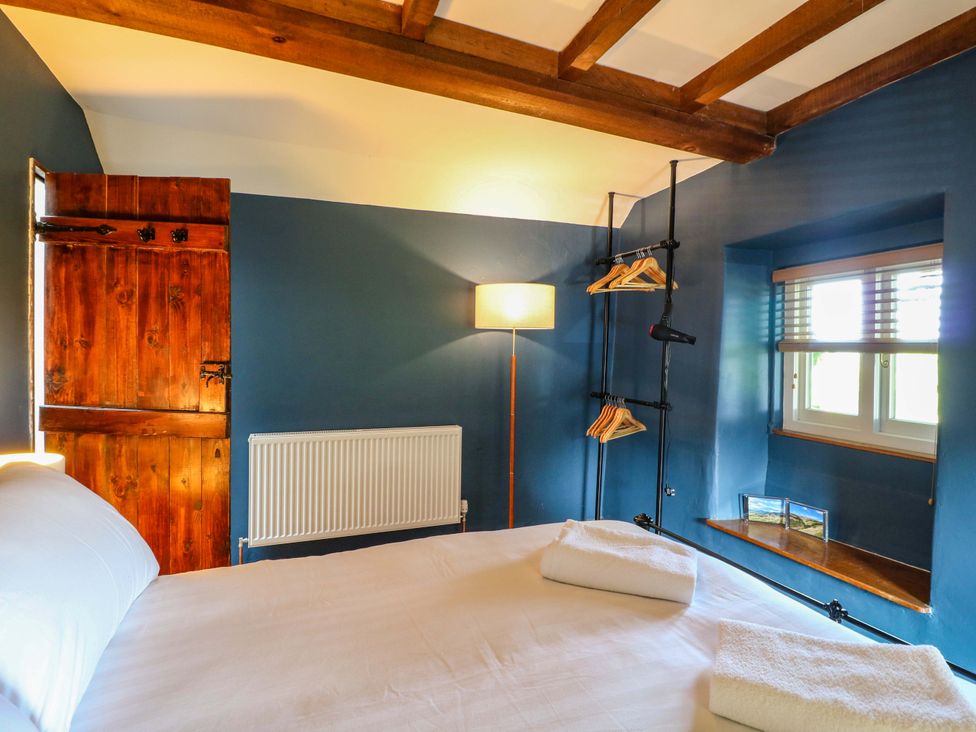 A bedroom with a bed and lamp at Chimney Cottage Winster