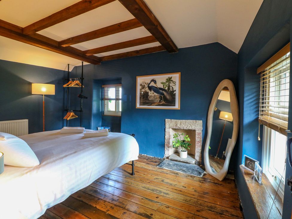 A bedroom with a bed, lamp and mirror at Chimney Cottage in Winster