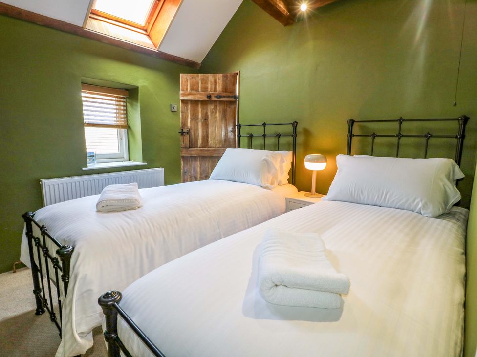 A bedroom with two beds and a lamp at Chimney Cottage in Winster