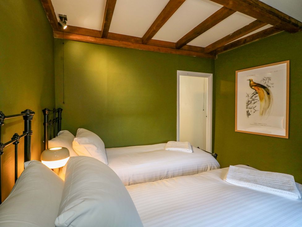 A bedroom with two beds and artwork at Chimney Cottage in Winster