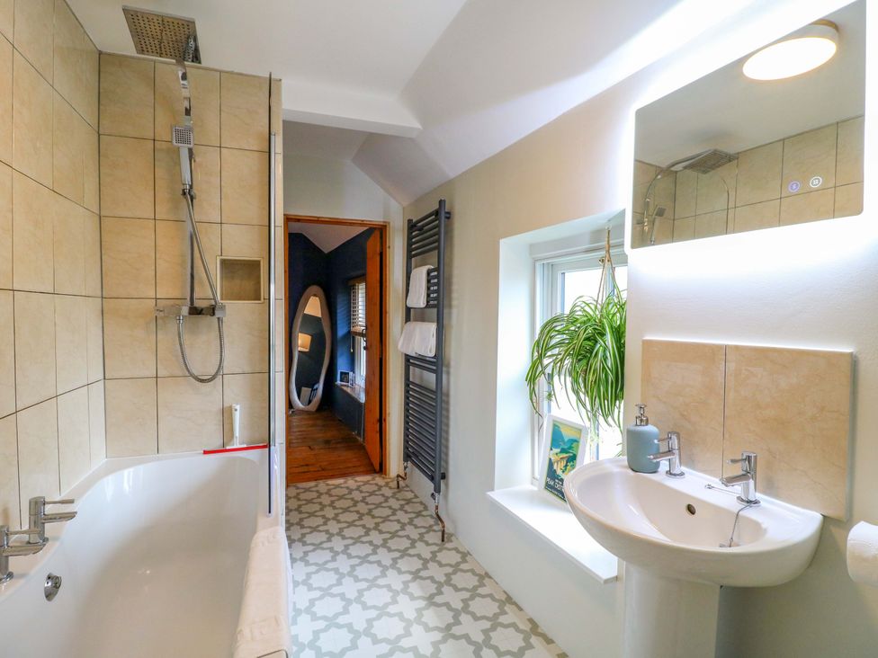 A bathroom with a shower and bathtub at Chimney Cottage in Winster