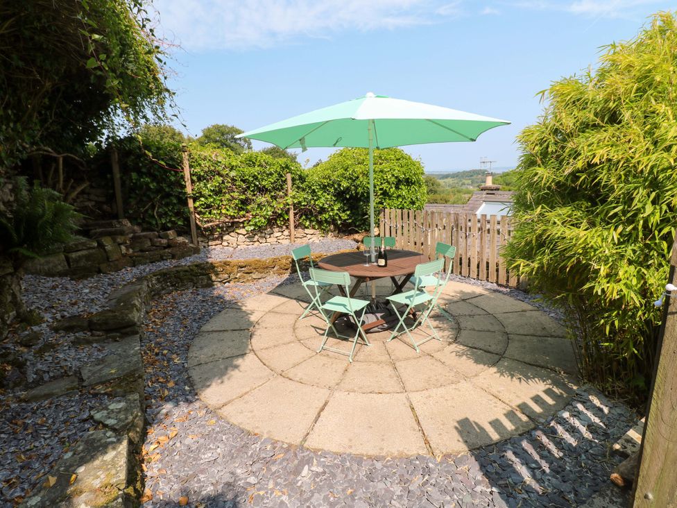 A garden with a table and chairs under an umbrella at Chimney Cottage in Winster