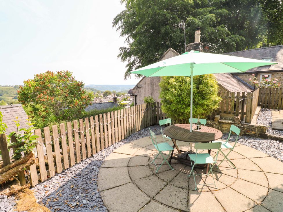 A garden with a round table and chairs under an umbrella at Chimney Cottage in Winster