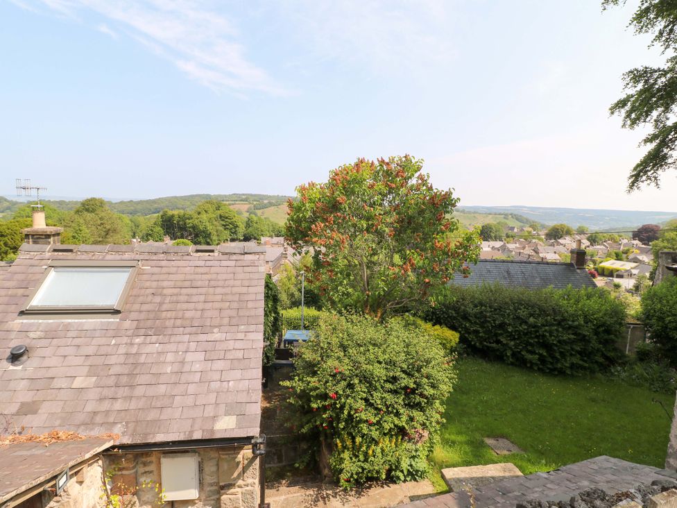 A view from a rooftop of a town with trees and hills at Chimney Cottage in Winster