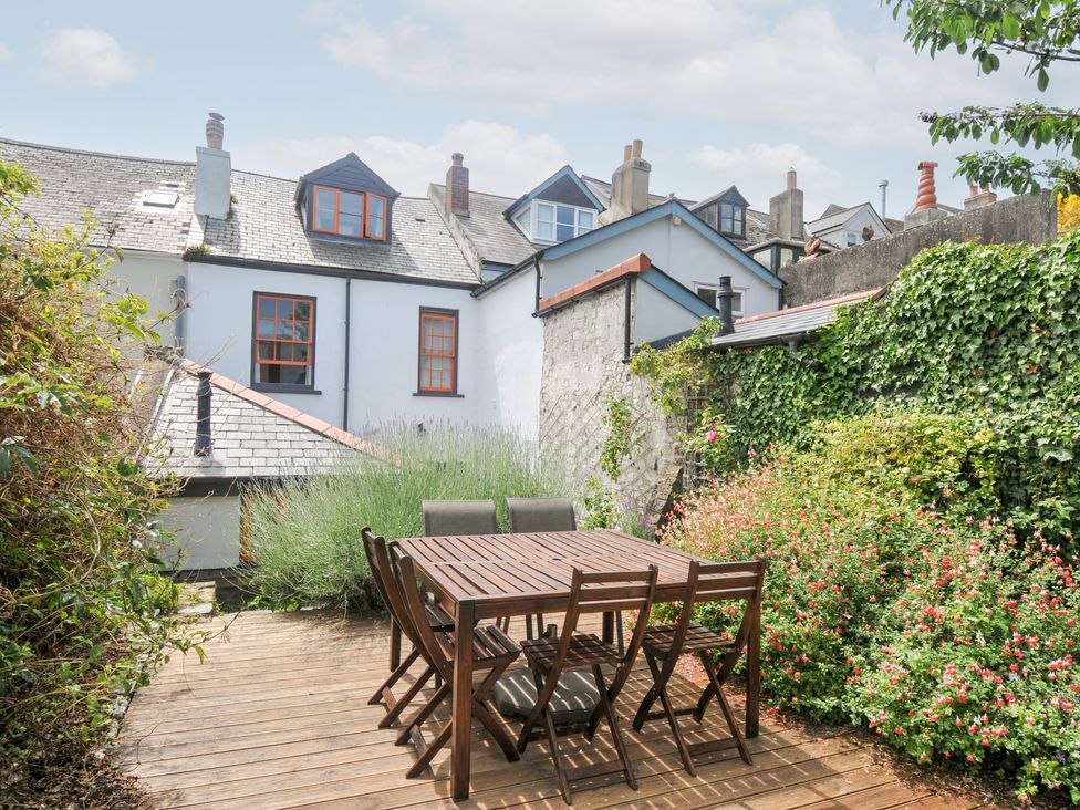 A garden with a wooden dining table and chairs at 12 Alpha Place Appledore