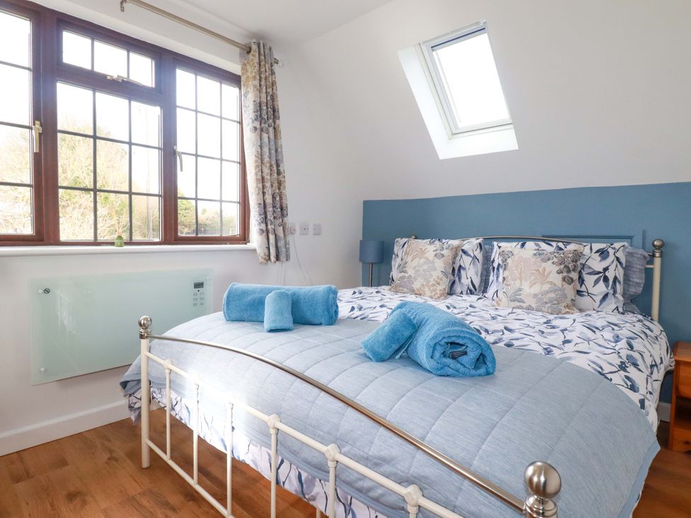 A bedroom with a bed and windows at Kernyk in Camelford