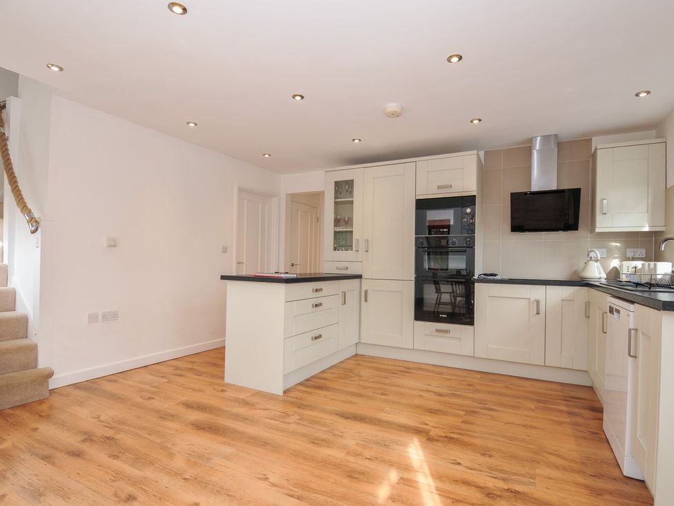 A kitchen with appliances and a staircase at Kernyk in Camelford