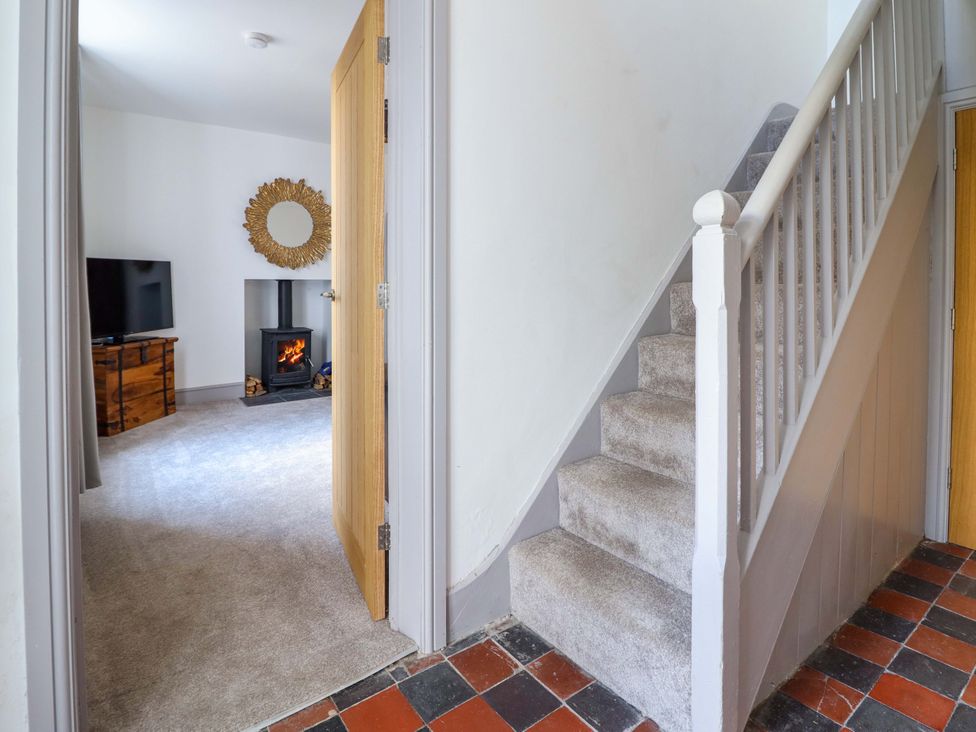 A hallway with a staircase and a view of a living room at The Farmhouse in Oswestry