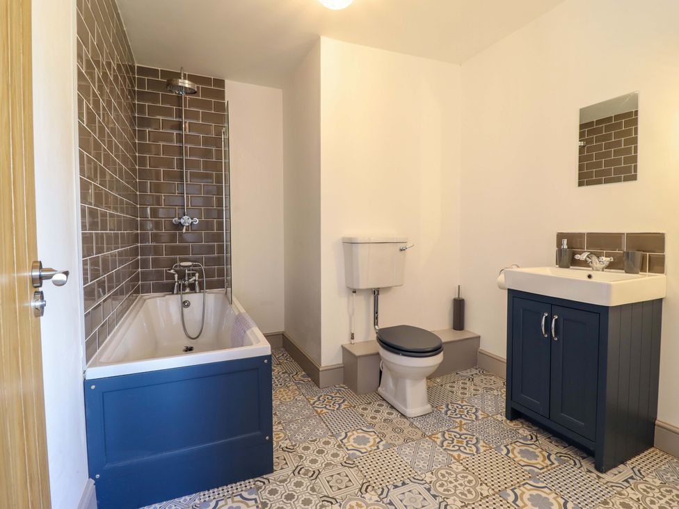 A bathroom with a bathtub, shower, toilet, and sink at The Farmhouse in Oswestry