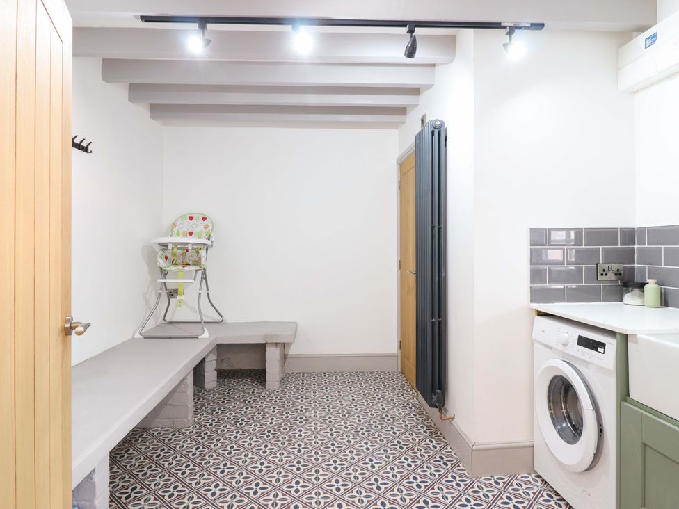 A utility room with a high chair and washing machine at The Farmhouse in Oswestry