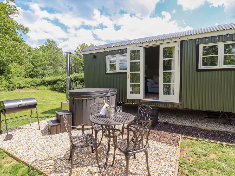 An outdoor space with a hot tub, table, chairs, and grill at Bluebell in Grimsby