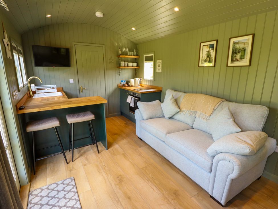 A living room with a couch and kitchen area at Bluebell in Grimsby