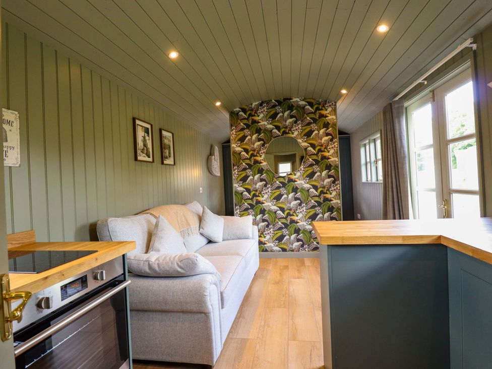 A living room with a sofa and kitchen counter at Bluebell in Grimsby
