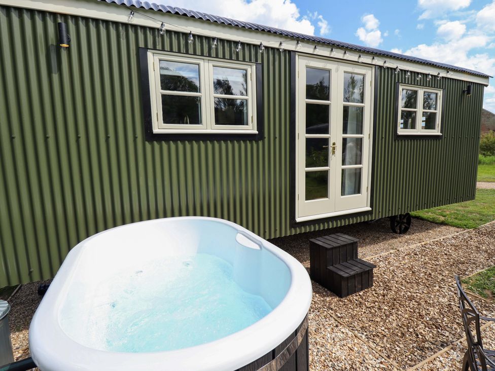 A hot tub next to a tiny house with windows and a door at Bluebell in Grimsby