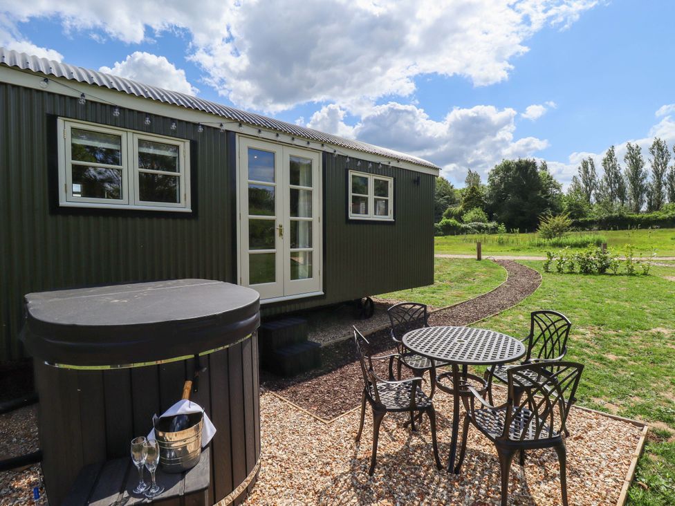An outdoor area with a hut, hot tub, table, and chairs at Bluebell in Grimsby
