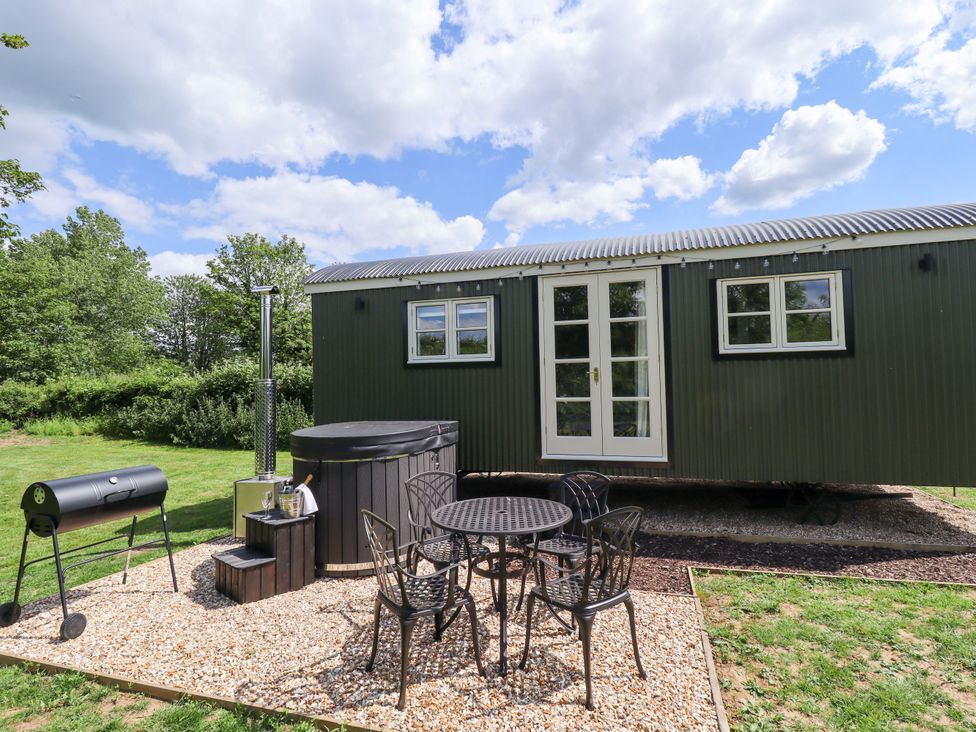 An outdoor area with a house, table, chairs, grill, and hot tub at Bluebell in Grimsby