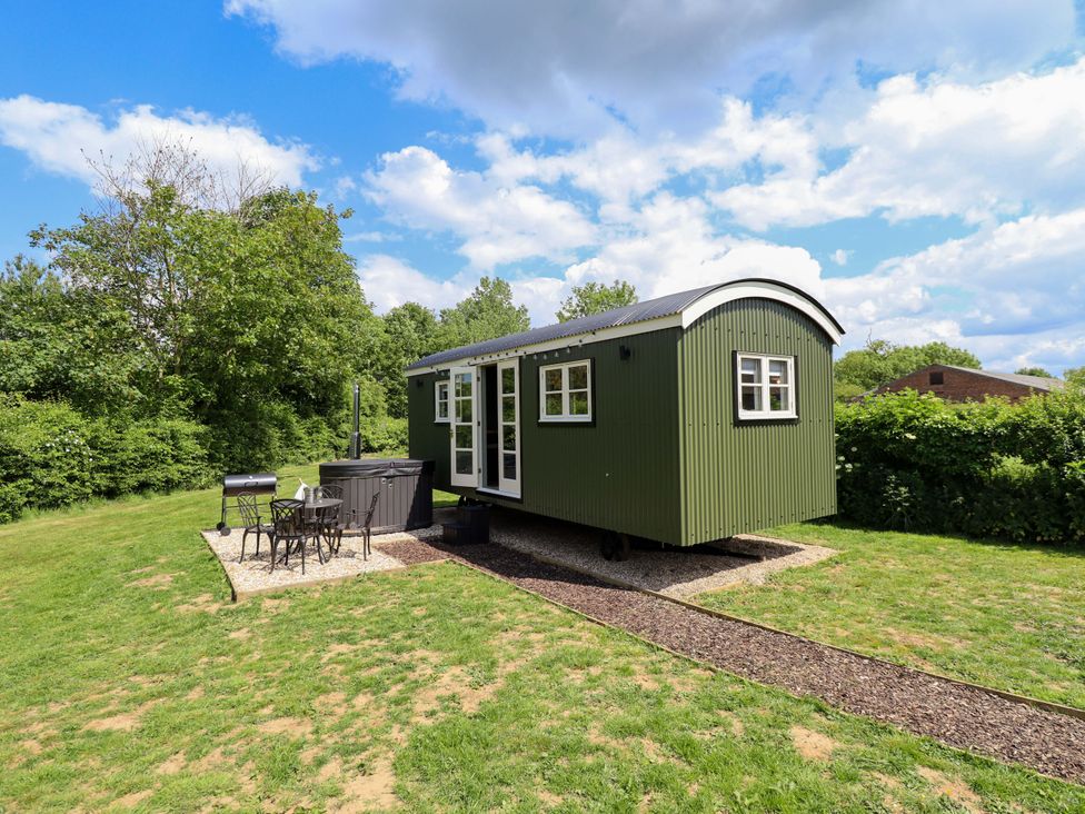 A shepherd's hut with a hot tub and outdoor seating area at Bluebell in Grimsby