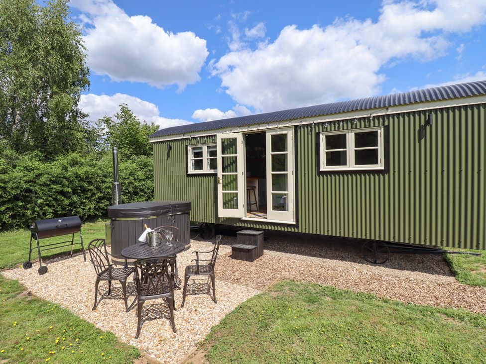 An outdoor area with a table and chairs next to a hot tub at Primrose Grimsby