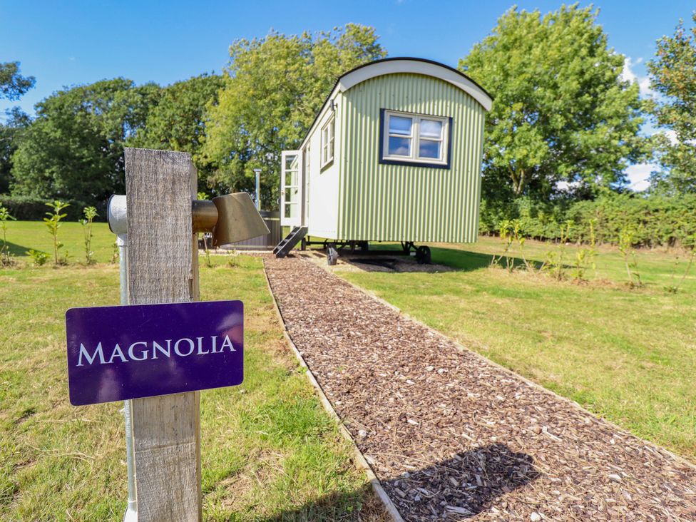 A shepherd's hut with a pathway and sign at Magnolia in Grimsby