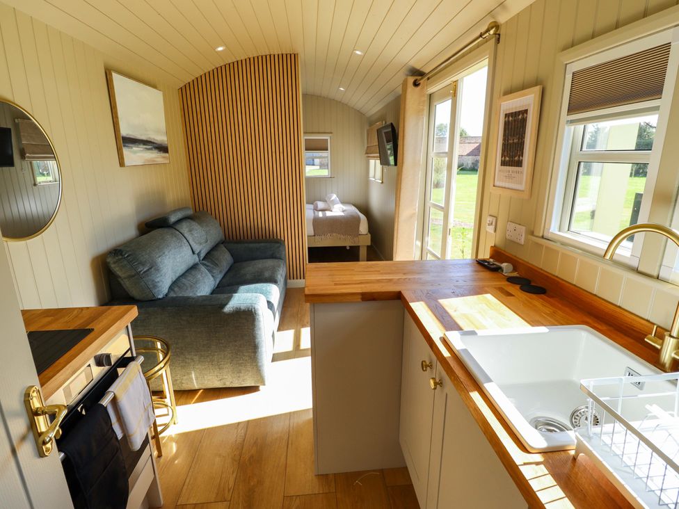 A living room with a sofa and kitchen area at Magnolia in Grimsby