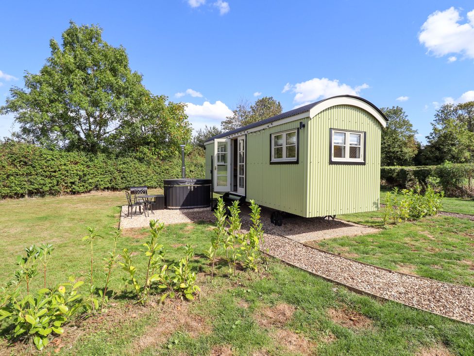 A shepherd's hut with outdoor seating and hot tub at Snowdrop in Grimsby