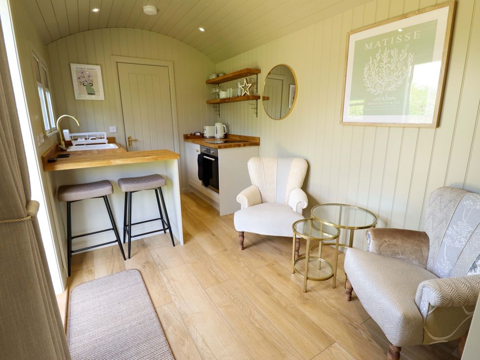 A living room with a kitchen counter and armchairs at Snowdrop in Grimsby