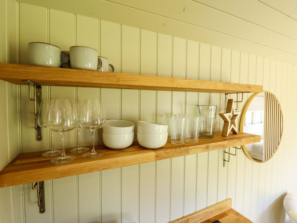 A kitchen shelf with mugs, glasses, and bowls at Snowdrop in Grimsby