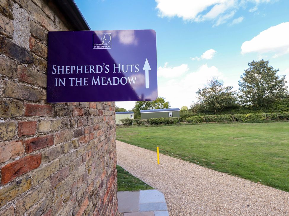 A sign indicating Shepherd's Huts in the Meadow with a pathway at Snowdrop in Grimsby