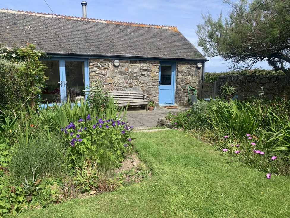 A garden with a stone building and bench at Stargazy Skies near Beacon Drive near St Agnes