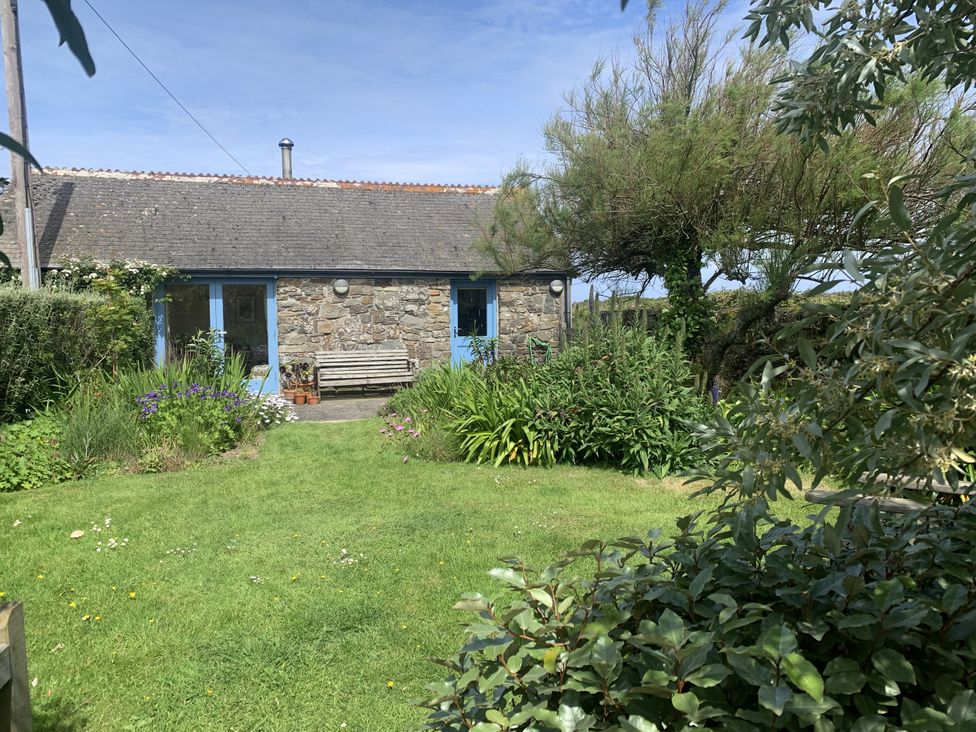 A stone building with blue doors and a bench in a garden at Stargazy Skies in Beacon Drive near St Agnes