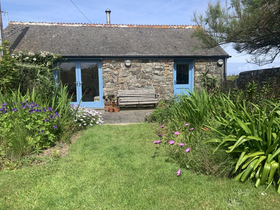 A stone cottage with blue door and flowers at Stargazy Skies, Beacon Drive near St Agnes