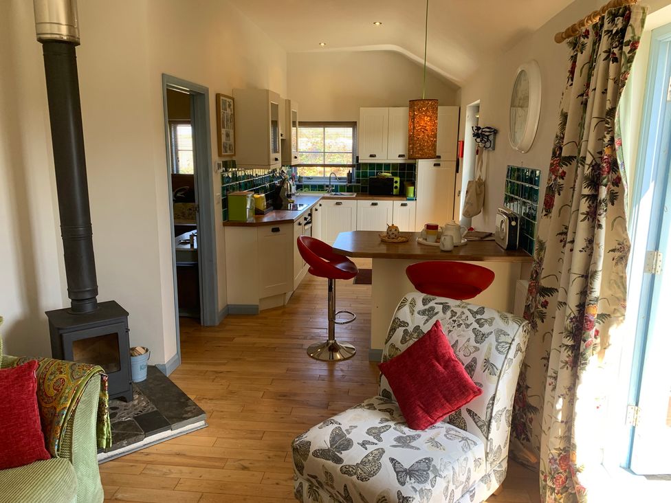 A kitchen with a stove and bar stools at Stargazy Skies near Beacon Drive near St Agnes