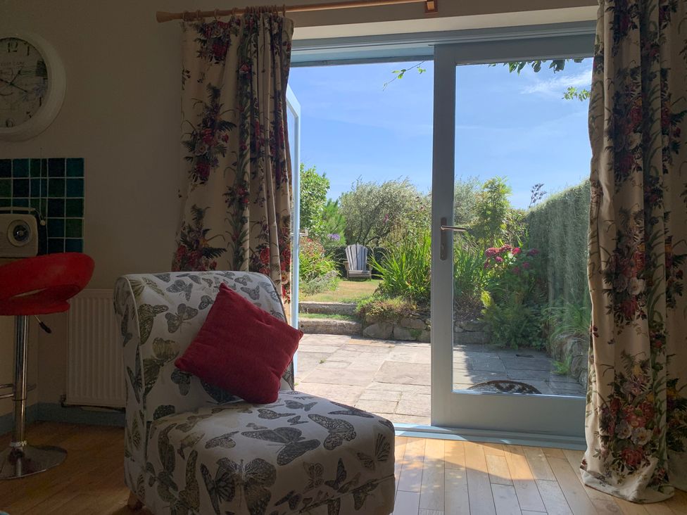 A living room with a chair and door opening to a garden at Stargazy Skies near Beacon Drive