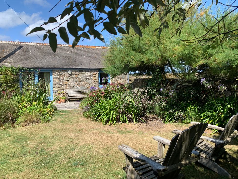 A garden with a stone building and wooden bench at Stargazy Skies near Beacon Drive near St Agnes