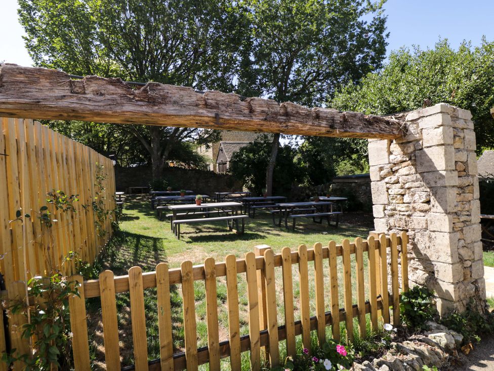 A garden area with tables and a wooden fence at Lorien in Bourton-On-The-Water