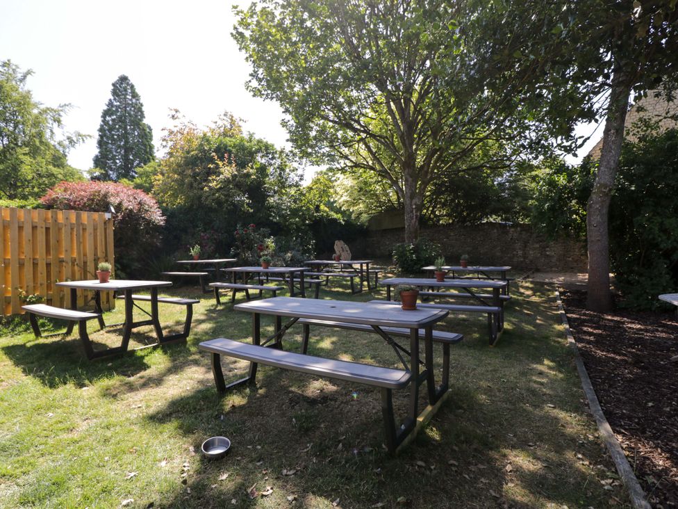 A garden with picnic tables and flower pots at Lorien in Bourton-On-The-Water