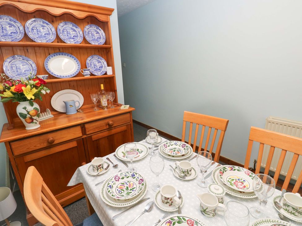 A dining room with a set table and sideboard at Graig Goch Burry Port