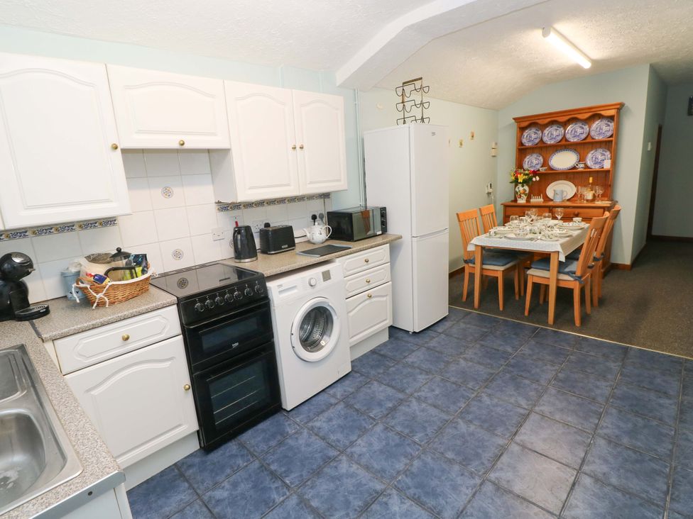 A kitchen with appliances and dining table at Graig Goch in Burry Port
