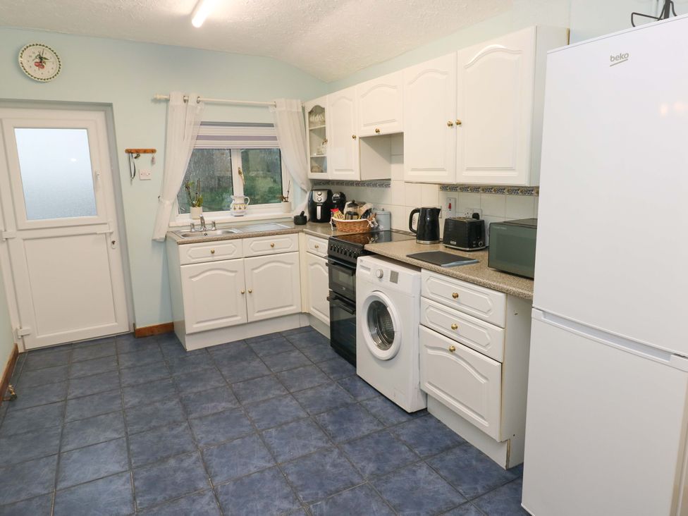 A kitchen with appliances and a sink at Graig Goch in Burry Port