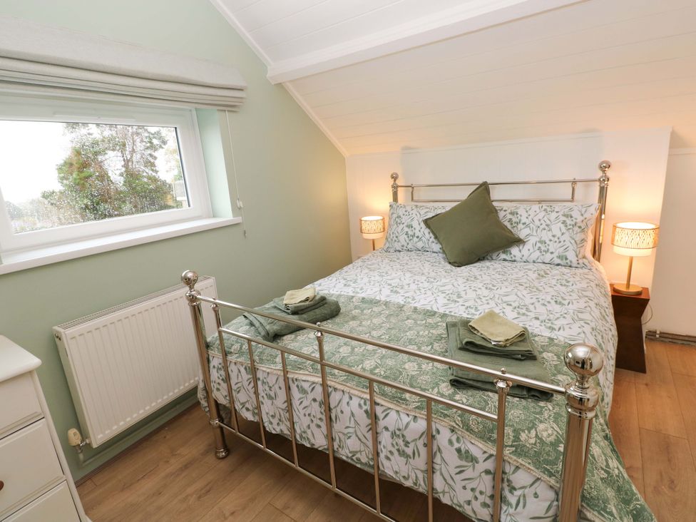 A bedroom with a bed and lamp at Graig Goch in Burry Port