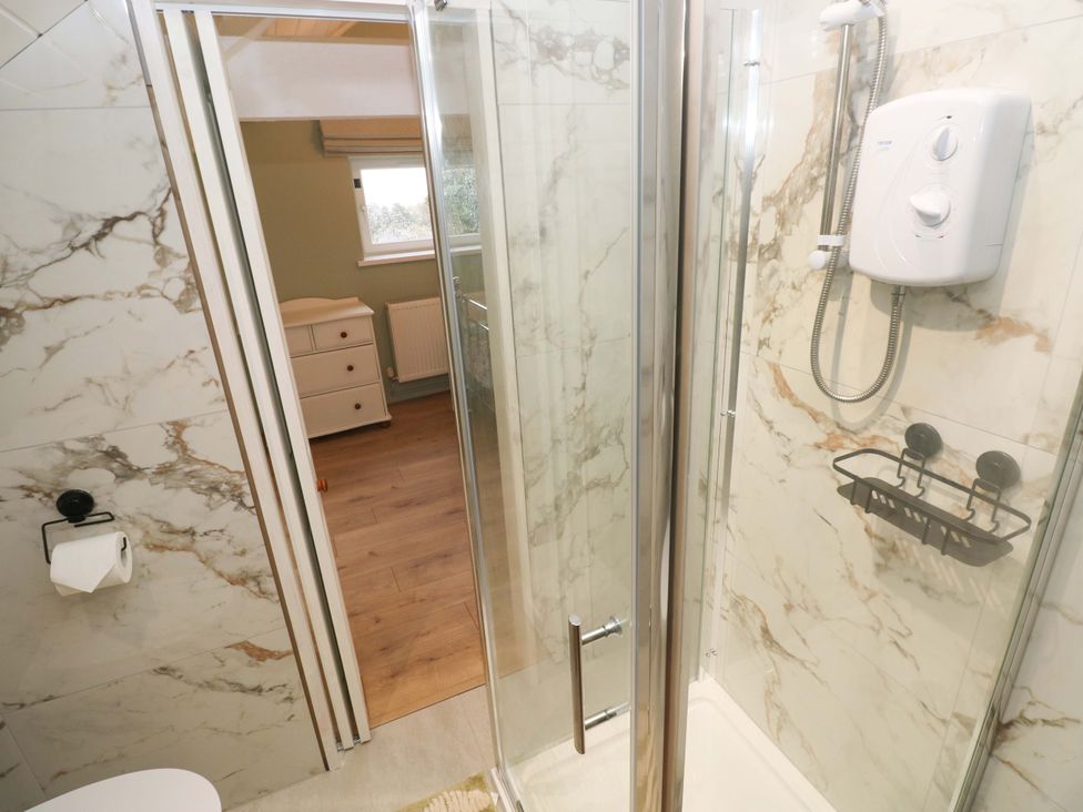 A bathroom with a shower and storage drawers at Graig Goch Burry Port