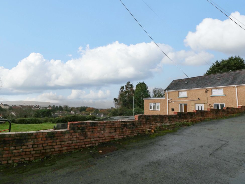 A house with a brick wall and grass in front at Graig Goch in Burry Port